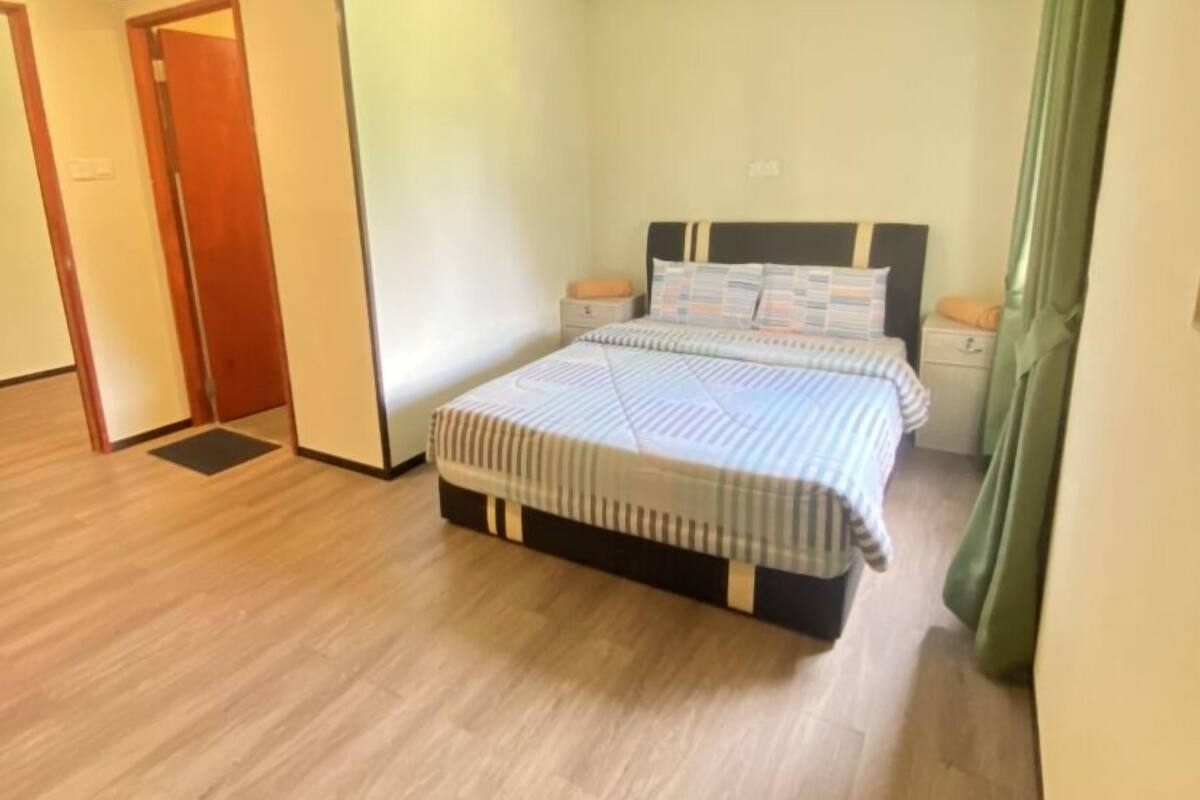 A bedroom with a bed, nightstands, and a green curtain.