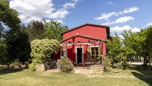 A red building with a stone entrance, surrounded by a grassy area and trees. - Eagle House (CHIANCIANO)