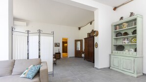 A living room with a beige sofa, a green cabinet with decorative items, and a hallway leading to another room. - Eagle House (CHIANCIANO)