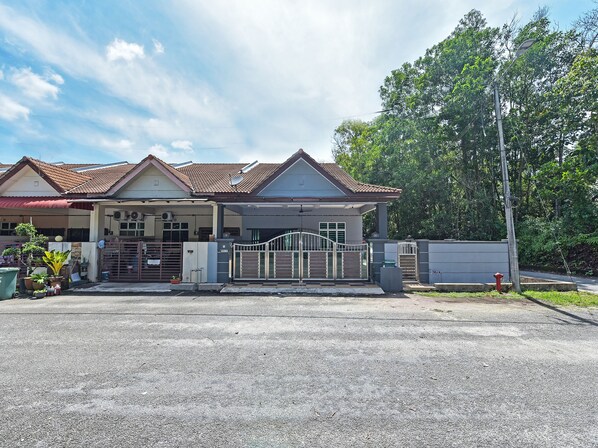 A two-story house with a tiled roof, a gated entrance, and a driveway.