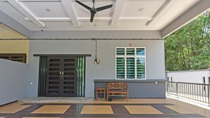 A spacious indoor area with a checkered floor, a ceiling fan, a wooden bench, and a window with blinds.