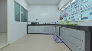 A modern kitchen with white tiled walls, stainless steel appliances, and a view of a residential building through the windows.