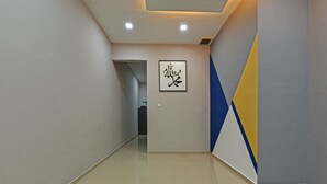 A hallway with a geometric wall design, a recessed ceiling, and a tiled floor.