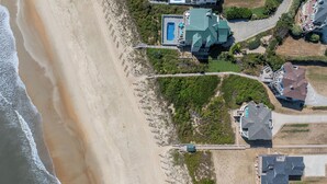 Luftaufnahme eines Küsteneigenguts mit Schwimmbad, mehreren Häusern und einem Strand.