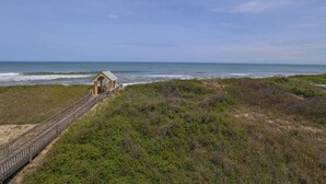 Ein Strand mit einer Holzpromenade, die zu einer kleinen Struktur führt.