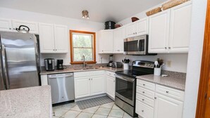 Una cucina con mobili bianchi, elettrodomestici in acciaio inossidabile, un forno a microonde e una lavastoviglie.