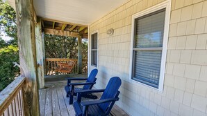 Eine überdachte Veranda mit zwei Adirondack-Stühlen und einer Holzterrasse.