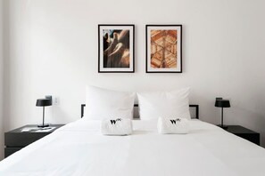 A hotel room with a large bed, two nightstands, two framed artworks, and white towels with a logo. - w* | Fantastic 1BR with Perfect Deco in Polanco (Ciudad de México)