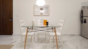 A modern kitchen with a glass dining table, white chairs, a hanging pendant light, and a framed picture on the wall. - w* | Upscale 1BR with Amazing Deco in Polanco (Ciudad de México)