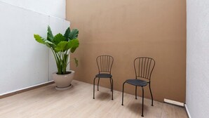 A small, enclosed space with a potted plant and two metal chairs against a white and brown wall. - w* | Upscale 1BR with Amazing Deco in Polanco (Ciudad de México)