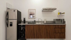 A compact kitchen with a built-in refrigerator, a microwave, and a sink. - w* | Upscale 1BR with Amazing Deco in Polanco (Ciudad de México)
