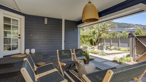 A covered outdoor seating area with wooden chairs and a woven ceiling light. - Luxury Living at the Beach (Stinson Beach)