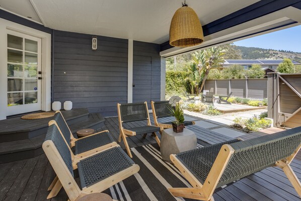 A covered outdoor seating area with wooden chairs and a woven ceiling light.