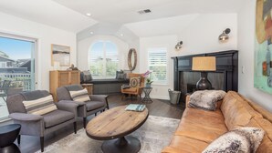 A spacious living room with a large window, a fireplace, and a cozy seating area. - Luxury Living at the Beach (Stinson Beach)