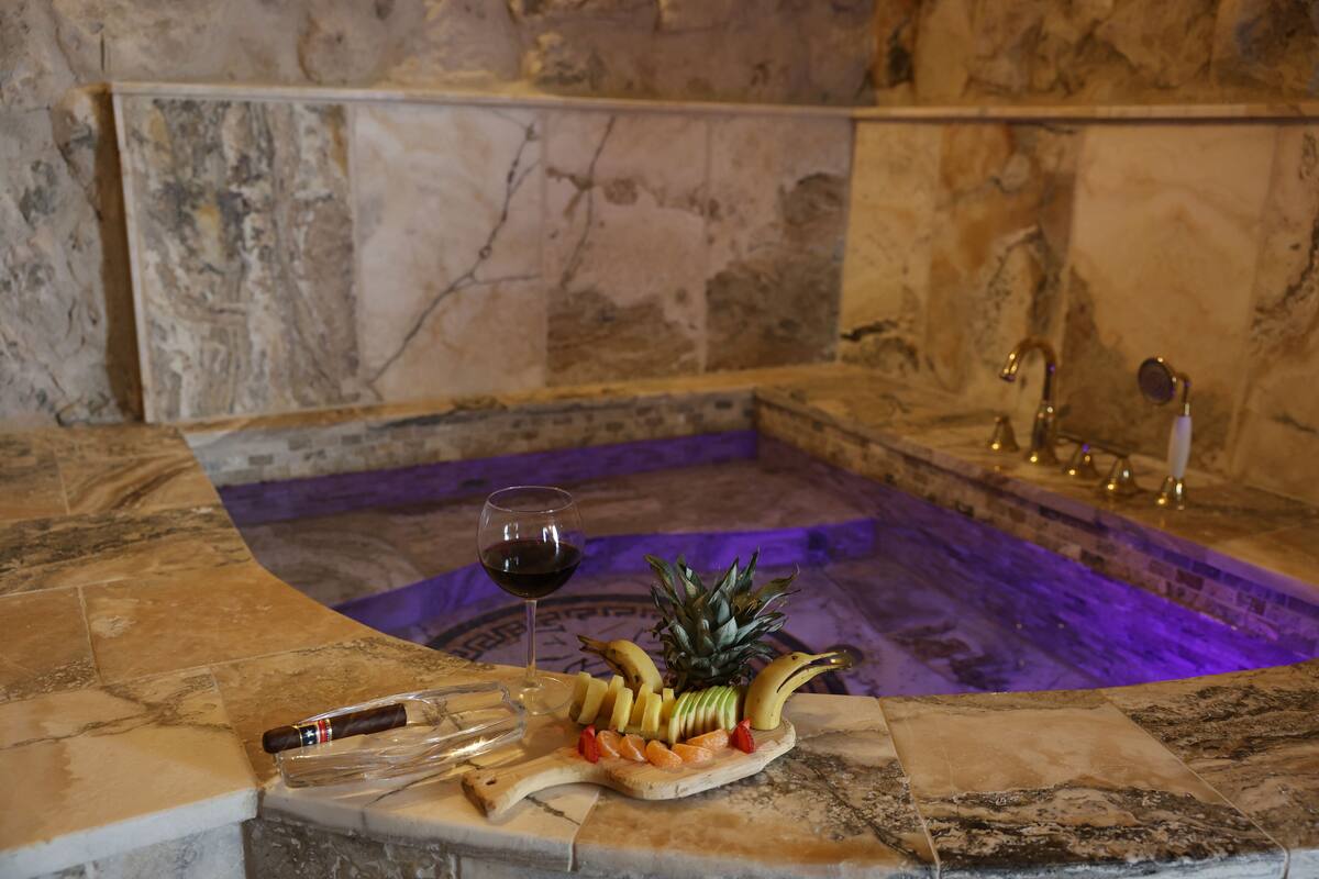 A marble bathtub with a glass of red wine and a fruit platter.