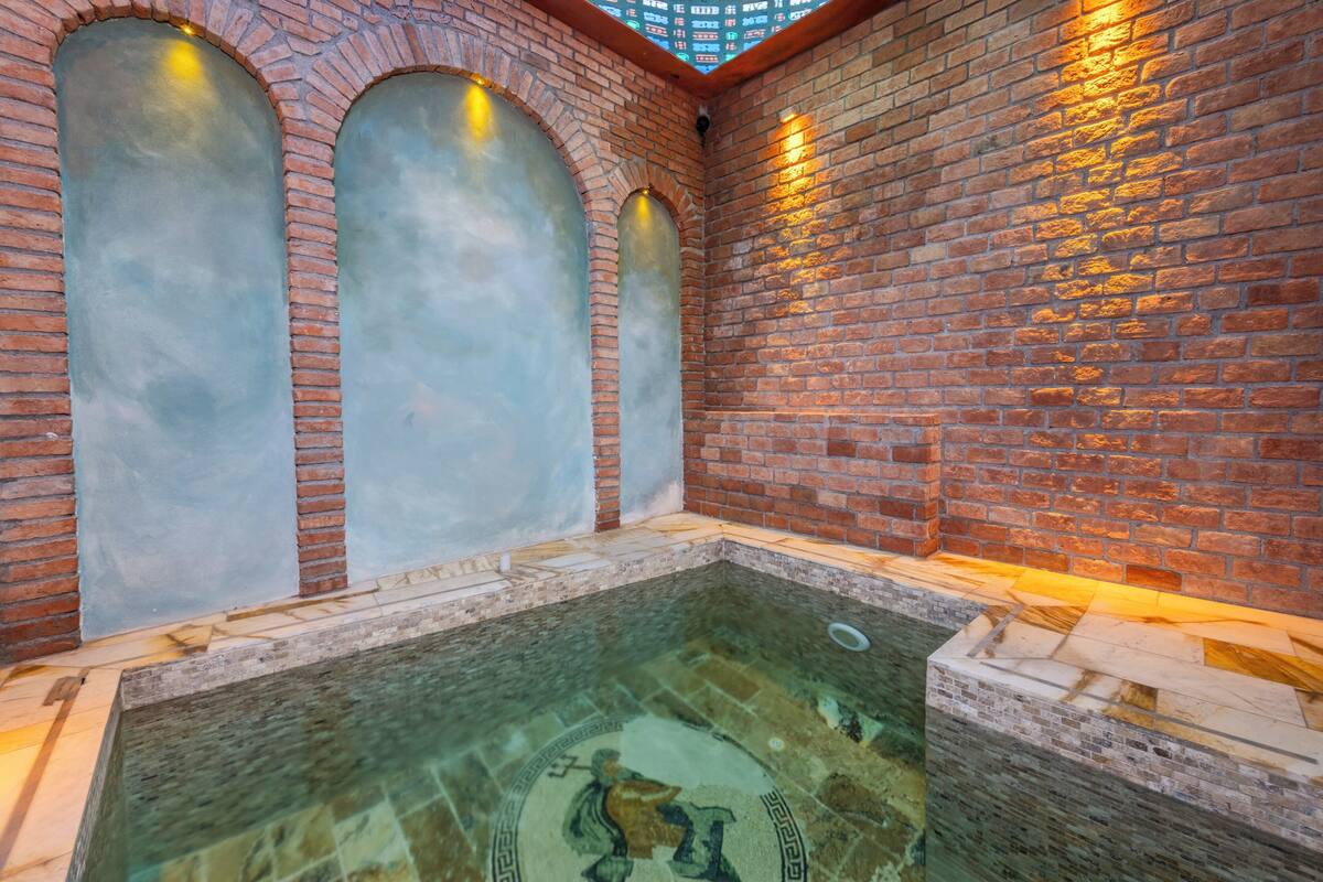 A spa area with a brick wall, three arched windows, and a tiled floor.
