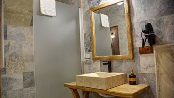 A bathroom with a marble wall, a wooden vanity, a large mirror, and a towel hanging on the door.