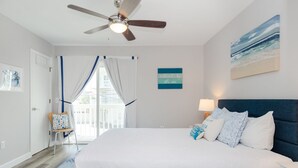 Un dormitorio con una cama grande, un ventilador de techo, vistas al exterior y un cuadro en la pared.