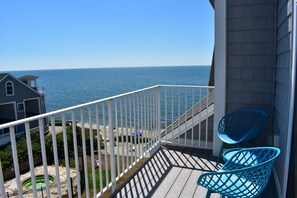 A balcony with a view of the ocean, two blue chairs, and a wooden deck. - Brand new Ocean View Condo with private balcony, steps from the beach! (Dennis Port)