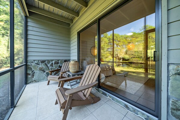 A covered outdoor seating area with wooden chairs and a stone wall backdrop.