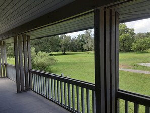 A covered porch with a view of a grassy yard and trees. - Modern/Elegant (Haines City)