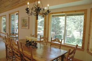 Enjoy meals in this spacious dining area with a large table and six chairs, surrounded by a beautiful forest view.