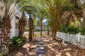 A pathway lined with palm trees and a white picket fence, leading to a building with a white exterior. - THE SURF SHACK / Sleeps 10 / POOL Plus HOT TUB and Pool House (Isle of Palms)