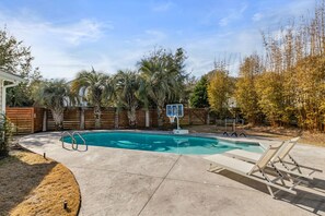 Ein Garten mit Swimmingpool, Liegestühlen und einem Basketballkorb.
