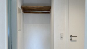 A narrow hallway with a wooden ceiling beam, a white door with a handle, and a light switch on the wall.