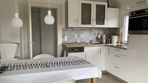 A modern kitchen with white cabinets, a wooden countertop, and a dining table with chairs.