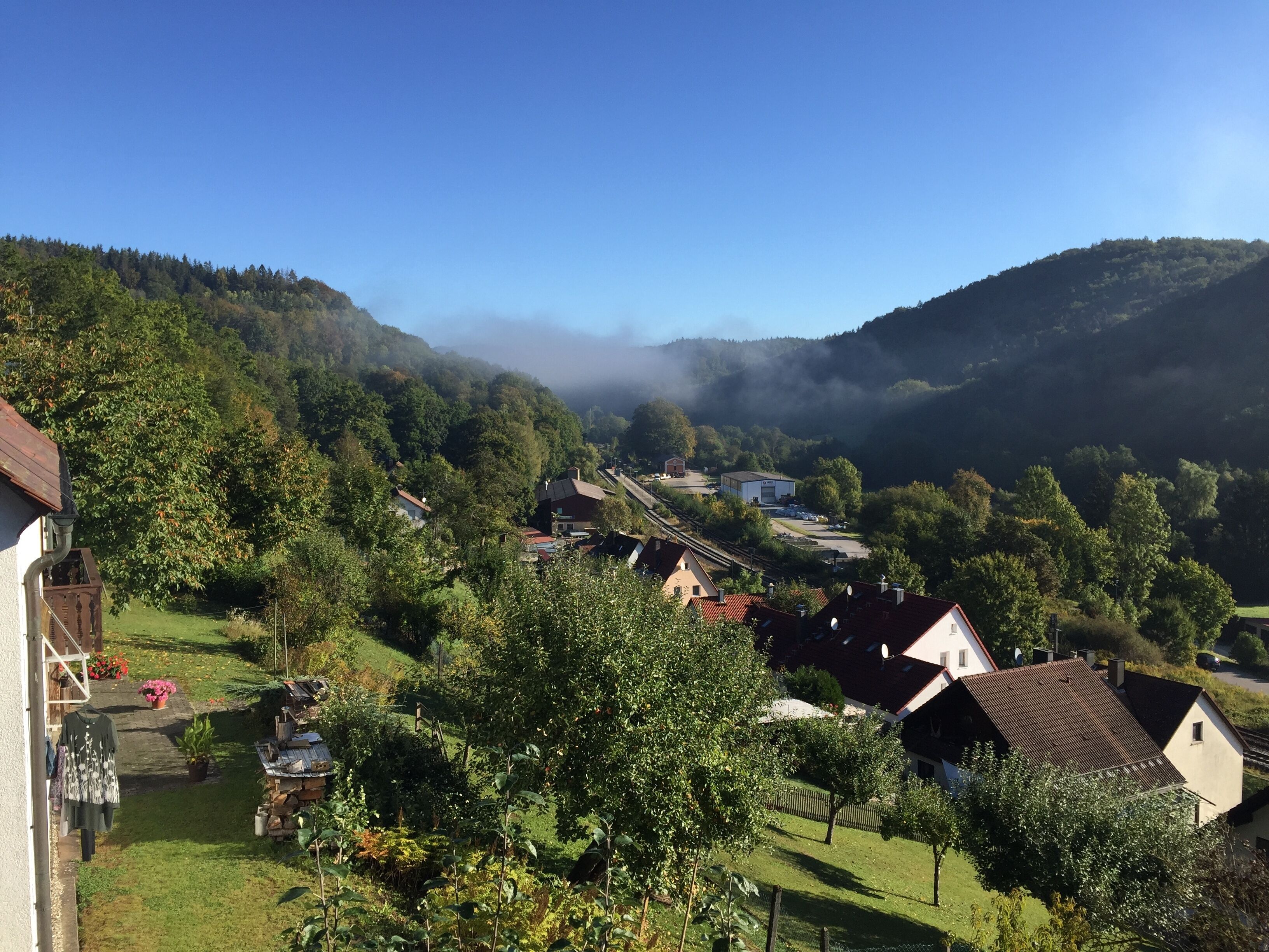 Un village rural avec des maisons, une petite route et une montagne en arrière-plan.