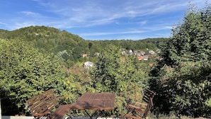 A patio with a table and chairs, overlooking a hillside with houses.