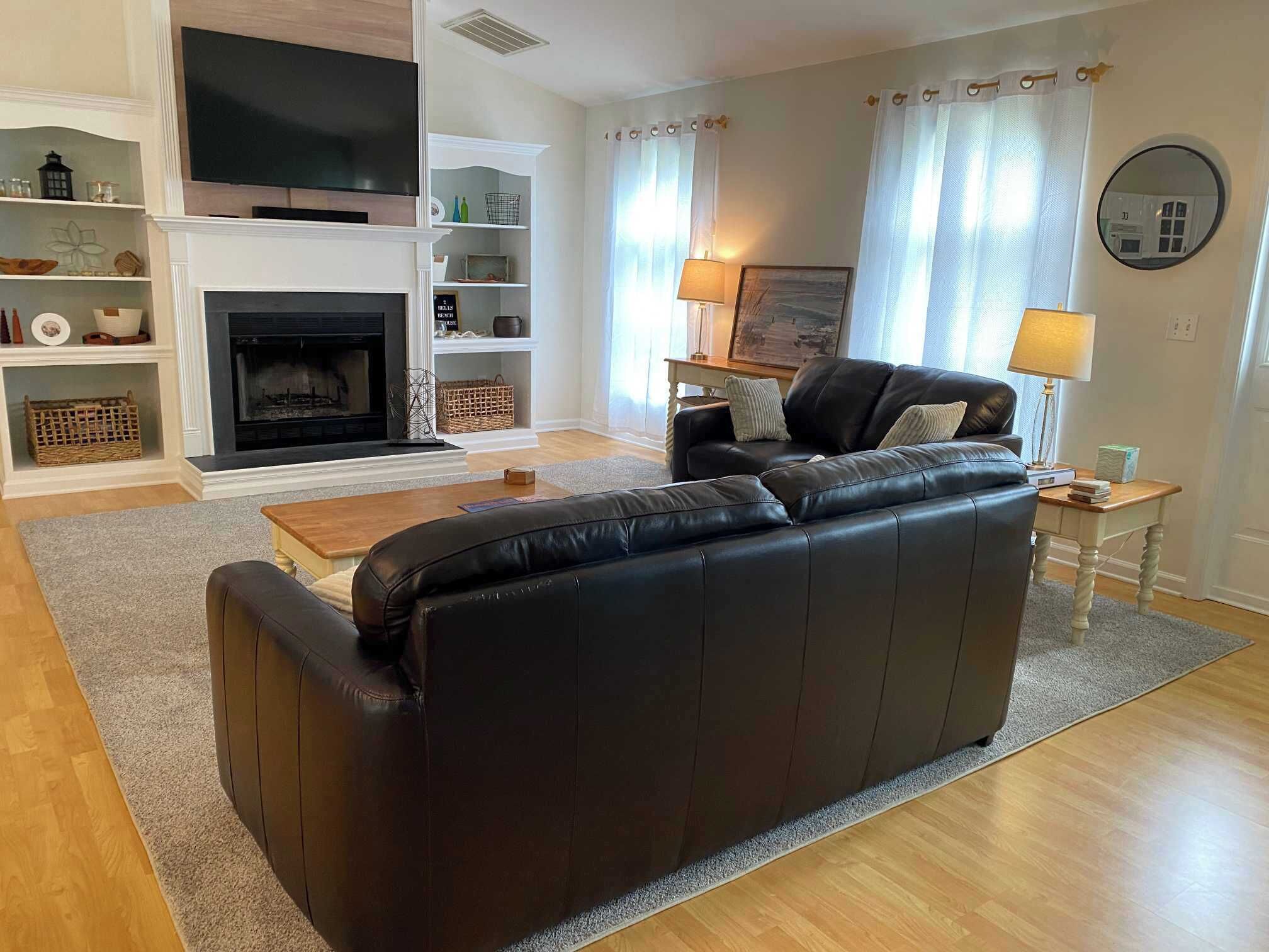A living room with a black leather sofa, a fireplace, a television, and a coffee table.