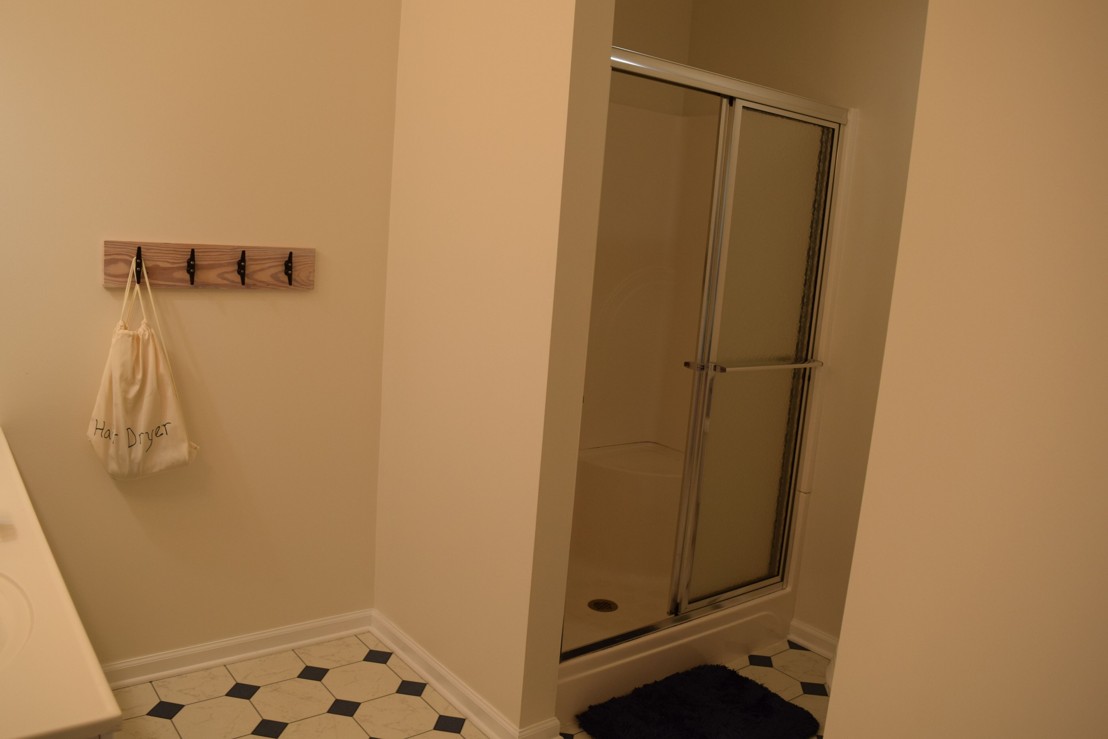 A bathroom with a shower, a towel rack, and a tiled floor.