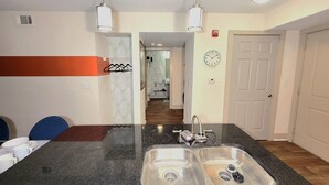 A kitchen with a stainless steel sink, a microwave, and a stove. There is a hallway leading to a bathroom with a shower and toilet. - World Cup-Ready! - Walk to MBS - Parking - ADA (Atlanta)