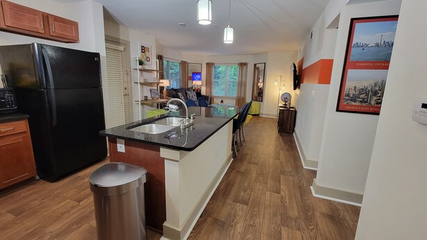 A modern kitchen with a black refrigerator, stainless steel sink, and wooden flooring. - World Cup-Ready! - Walk to MBS - Parking - ADA (Atlanta)