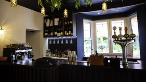 A bar area with a coffee machine, shelves of bottles, and a tap with beer taps.