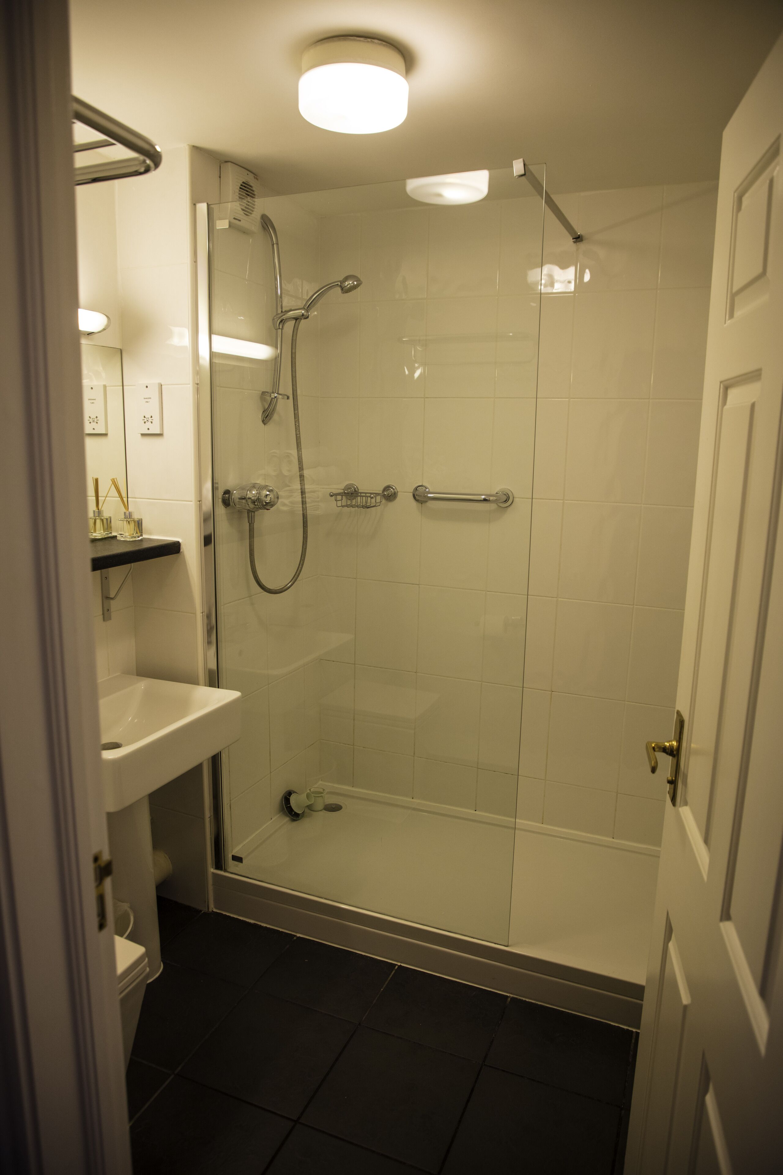 Un bagno moderno con cabina doccia in vetro, lavandino bianco e water.
