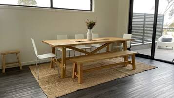 A modern dining area with a wooden table, white chairs, and a bench.