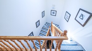 A staircase with wooden balusters and a handrail, leading to a landing with framed pictures on the walls. - La Posada de la Gula (Jarandilla de la Vera)