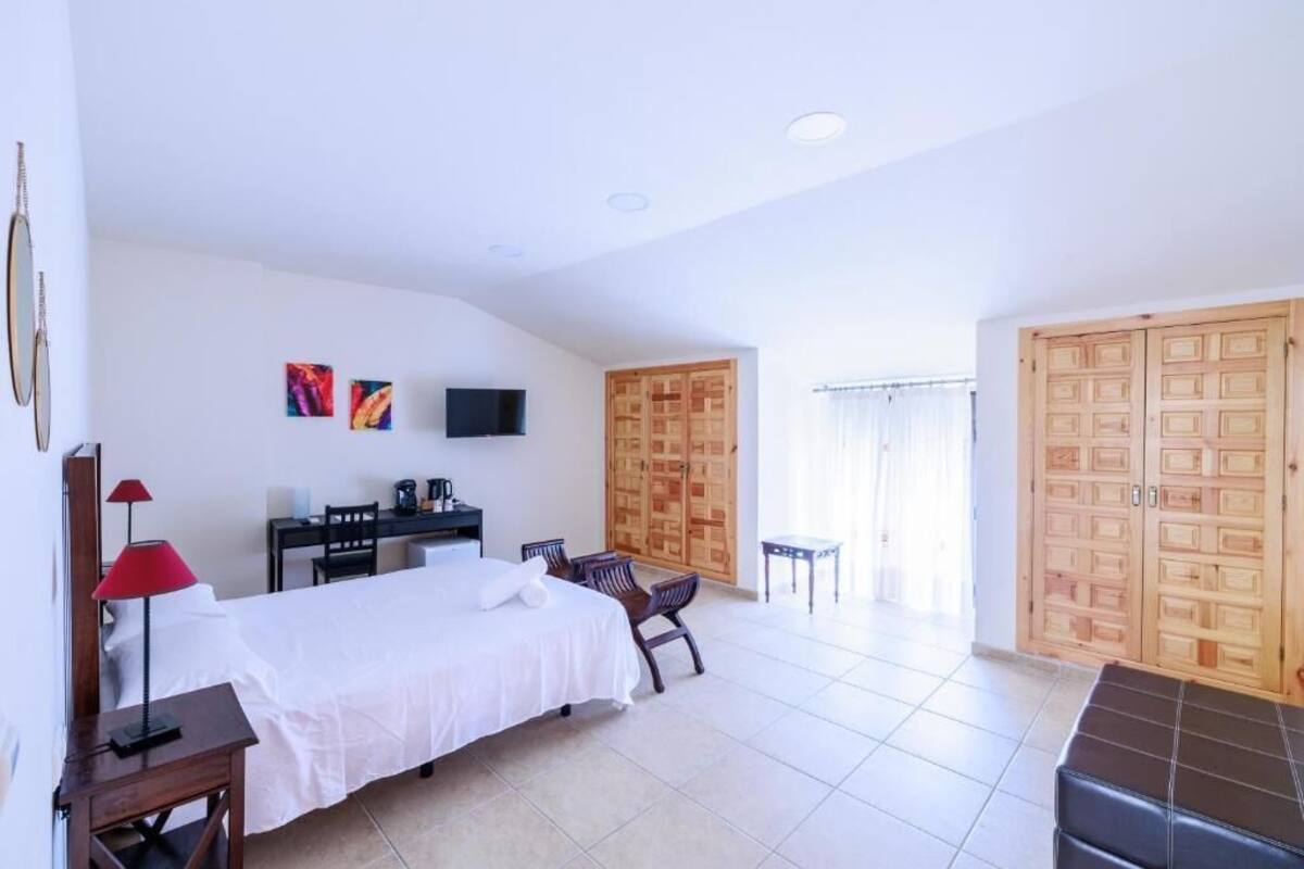 Un dormitorio amplio con cama, escritorio, silla, televisor y armarios de madera.
