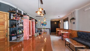 A bar area with a polished wooden bar, shelves with bottles, a laptop, and hanging pendant lights. - La Posada de la Gula (Jarandilla de la Vera)