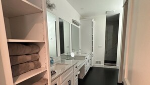 Ein modernes Badezimmer mit dunklem Boden, weißen Schränken und einem großen Spiegel.