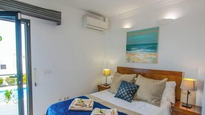 Una camera d'hotel con un letto, un quadro che raffigura il mare, un condizionatore d'aria e vista sull'esterno.