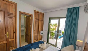 Une chambre d’hôtel avec un lit, un ventilateur, une vue sur l’extérieur et des portes en bois.