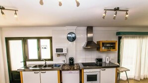 Una cucina con piano cottura, lavandino, forno a microonde e orologio a parete.