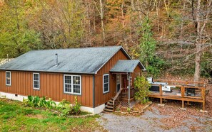 Escape to a secluded cabin surrounded by dense woods, featuring a cozy porch and a deck perfect for relaxation.