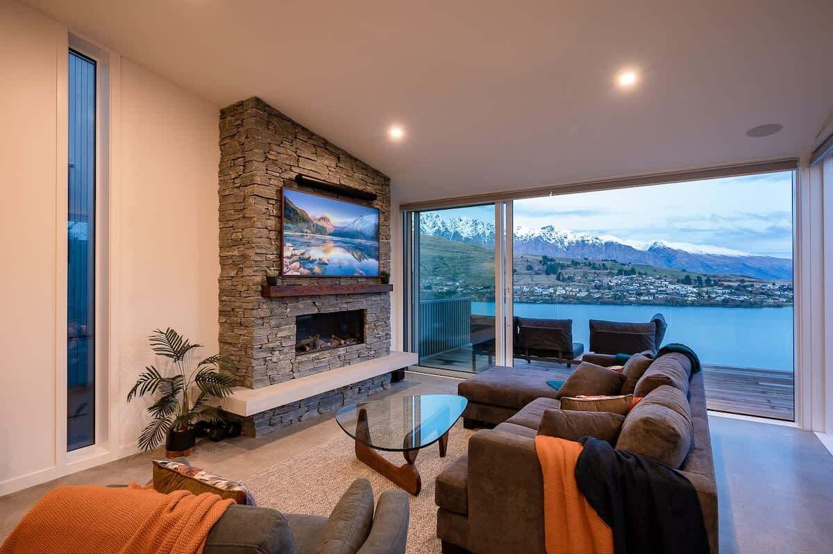 A modern living room with a stone fireplace, a large window with a mountain view, and a cozy seating area.