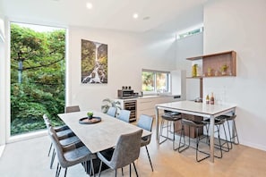 Une cuisine moderne avec un coin repas, de grandes fenêtres et une vue sur la verdure.
