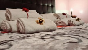 Neatly folded towels with decorative brooches on a patterned bedspread in a hotel room. - Augustus Room (Roma)
